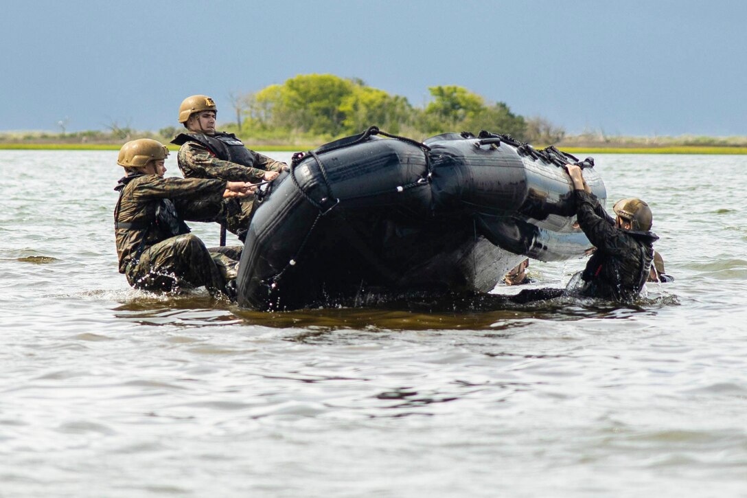 Marines pull on an inflatable boat to flip it while in water.