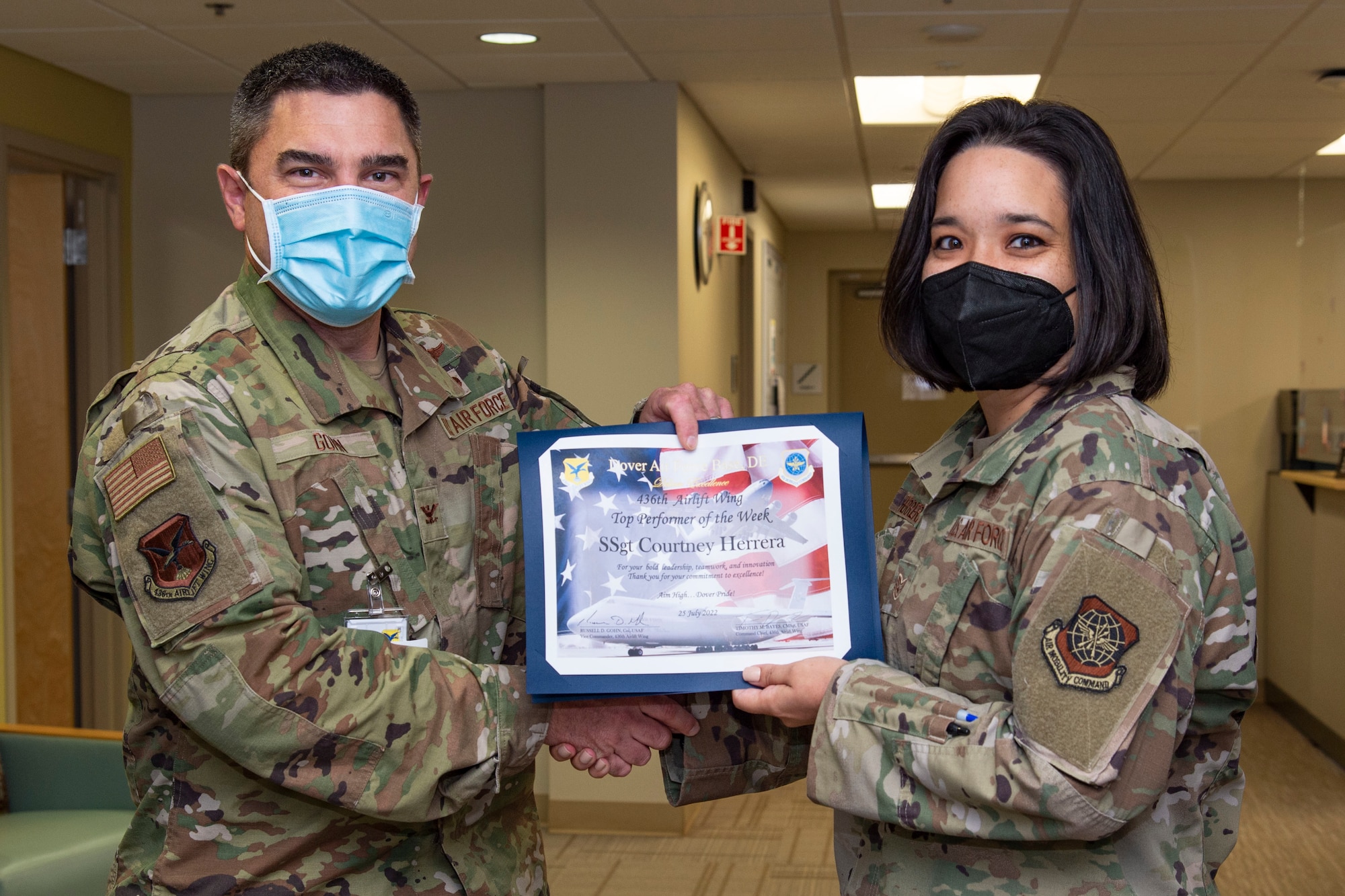 Col. Rusty Gohn, left, 436th Airlift Wing vice commander, presents Staff Sgt. Courtney Herrera, right, 436th Medical Group senior enlisted leader executive officer, with a certificate as the week's Top Performer on Dover Air Force Base, Delaware, July 26, 2022. Herrera also was coined by Gohn for her outstanding performance. (U.S. Air Force photo by Roland Balik)