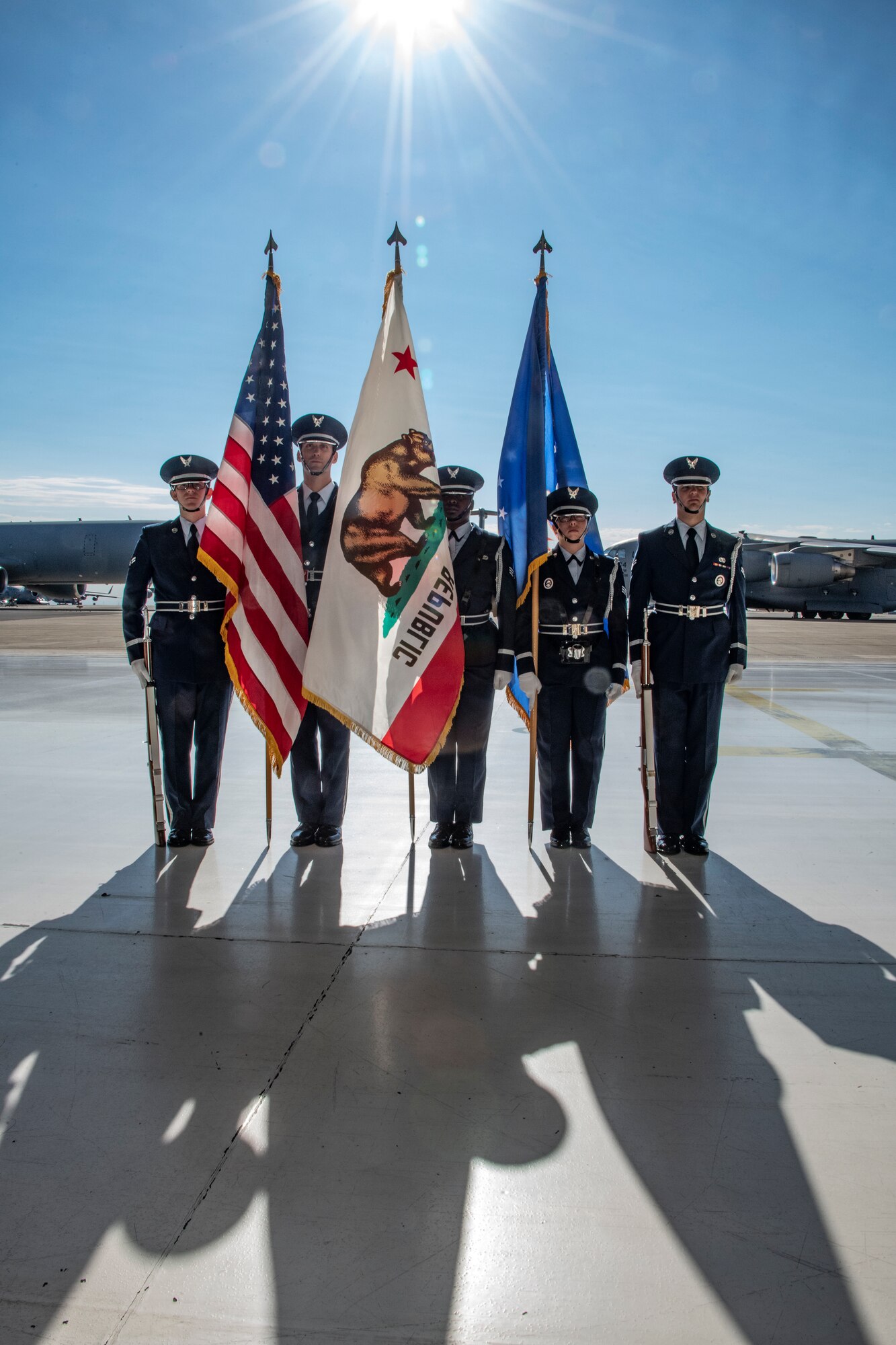 5 Airmen stand stand, 3 hold a flag each.