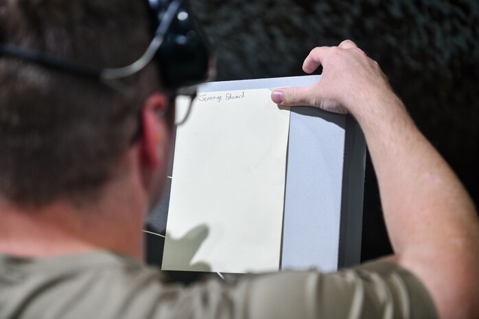 U.S. Air Force Senior Airman Edward Jennings, 628th Security Forces Raven team member, signs his name to a practice target during the Excellence in Competition Pistol Shoot