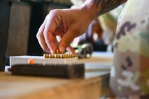 U.S. Air Force Senior Airman Shan Craddock, 628th Security Forces Raven team member, loads rounds into his magazine during the Excellence in Competition Pistol Shoot
