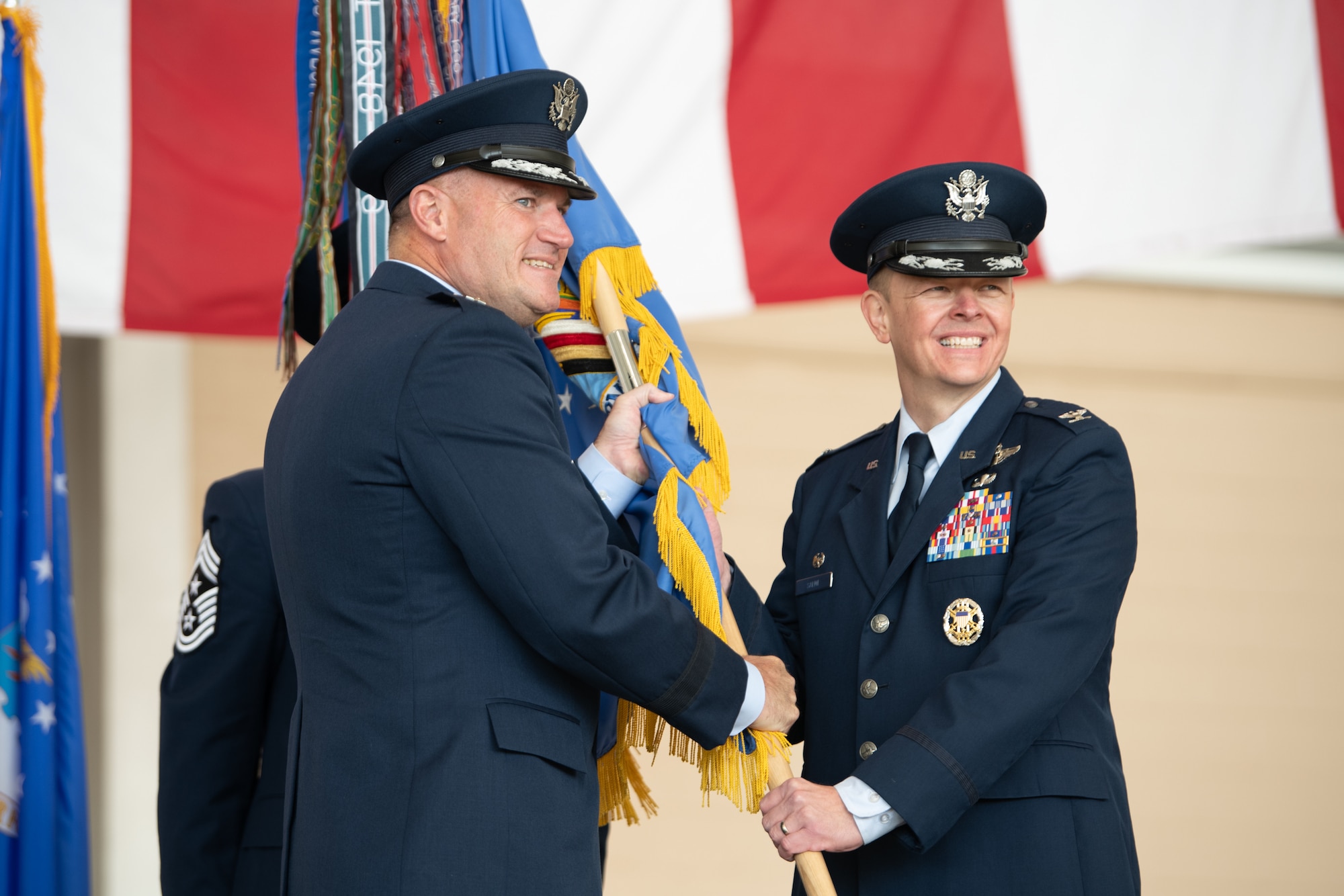 Two higher ranking Airmen hold a flag.