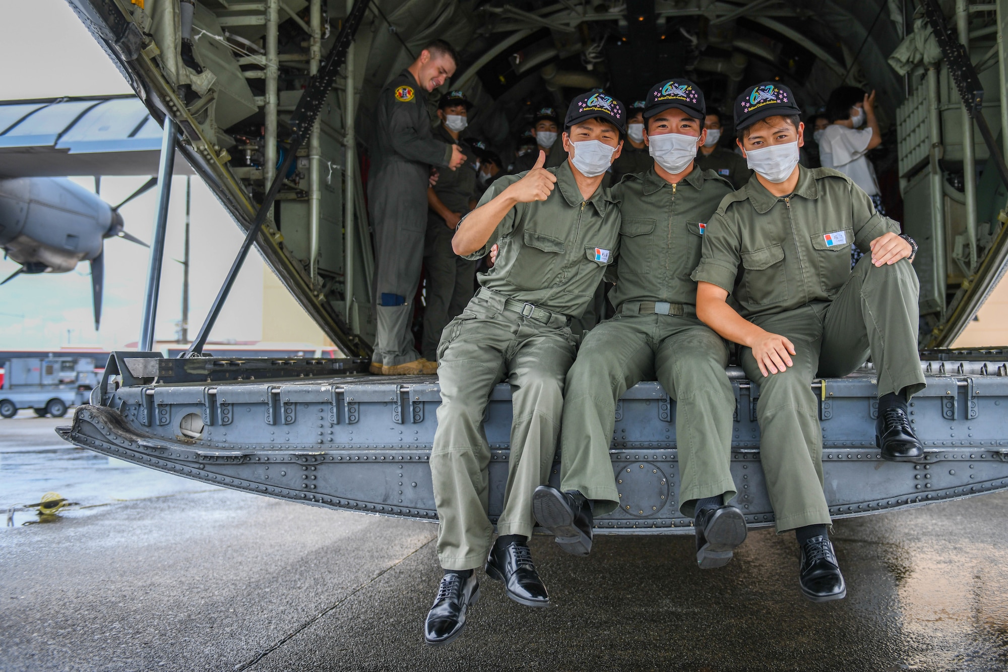 Cadets sit on the loading ramp of a C-130J