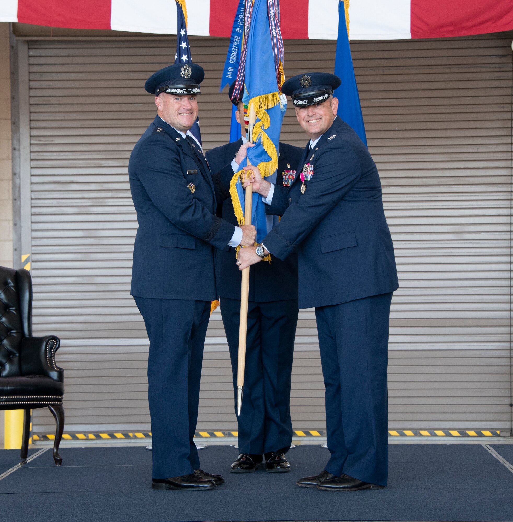 U.S. Air Force Maj. Gen. Kenneth Bibb, left, 18th Air Force commander, accepts the guidon from Col. Corey Simmons, right, outgoing 60th Air Mobility Wing commander, during the 60th AMW change of command ceremony at Travis Air Force Base, California, July 27, 2022. Bibb was the presiding officer for the change of command ceremony. (U.S. Air Force photo by Heide Couch)