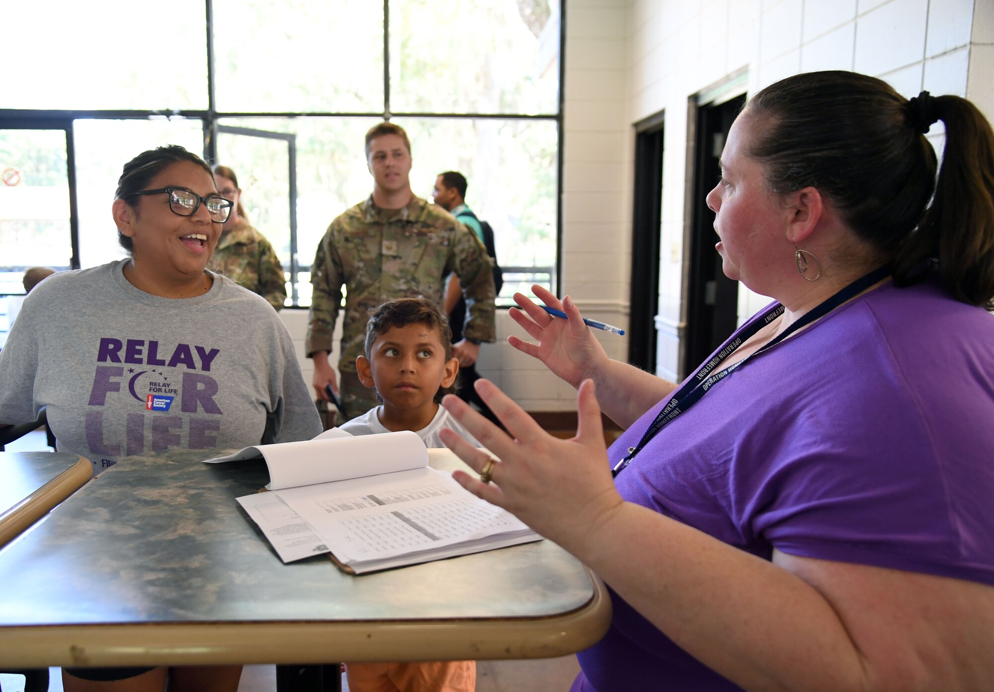 Teressa Vieira, wife of Jon Vieira, 81st Logistics Readiness Squadron vehicle operator, checks families in during a Back to School Bash at the Keesler Marina on Keesler Air Force Base, Mississippi, July 28, 2022. The bash, a collaboration of agencies that included Operation Homefront, the Back-to-School Brigade and Keesler support agencies, provided families with nearly 200 bookbags filled with supplies and included games and free snow cones. (U.S. Air Force photo by Kemberly Groue)