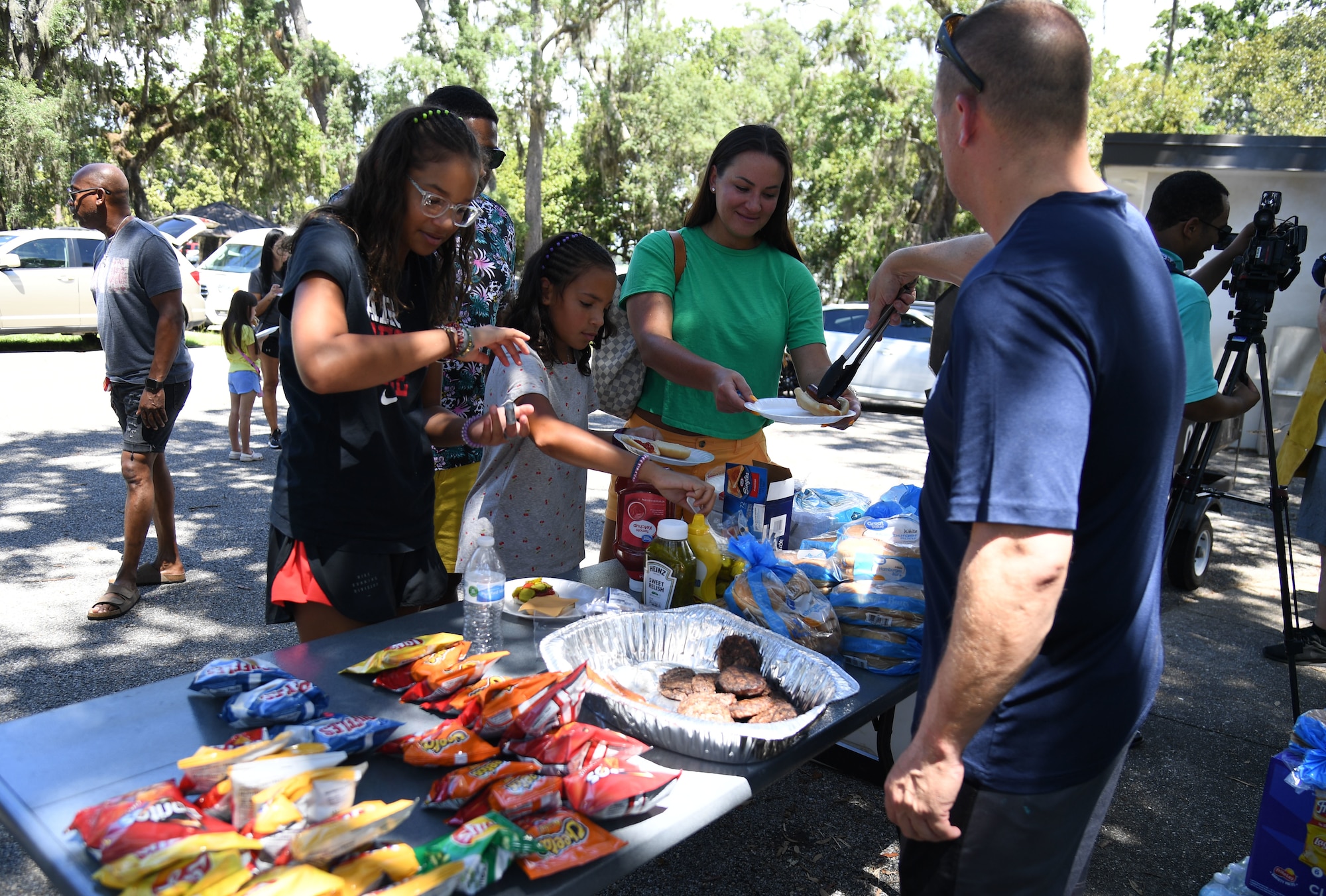 U.S. Air Force Chief Master Sgt. Don Burkhart, Second Air Force training pipeline manager, distributes food to Keesler families during a Back to School Bash at the Keesler Marina on Keesler Air Force Base, Mississippi, July 28, 2022. The bash, a collaboration of agencies that included Operation Homefront, the Back-to-School Brigade and Keesler support agencies, provided families with nearly 200 bookbags filled with supplies and included games and free snow cones. (U.S. Air Force photo by Kemberly Groue)
