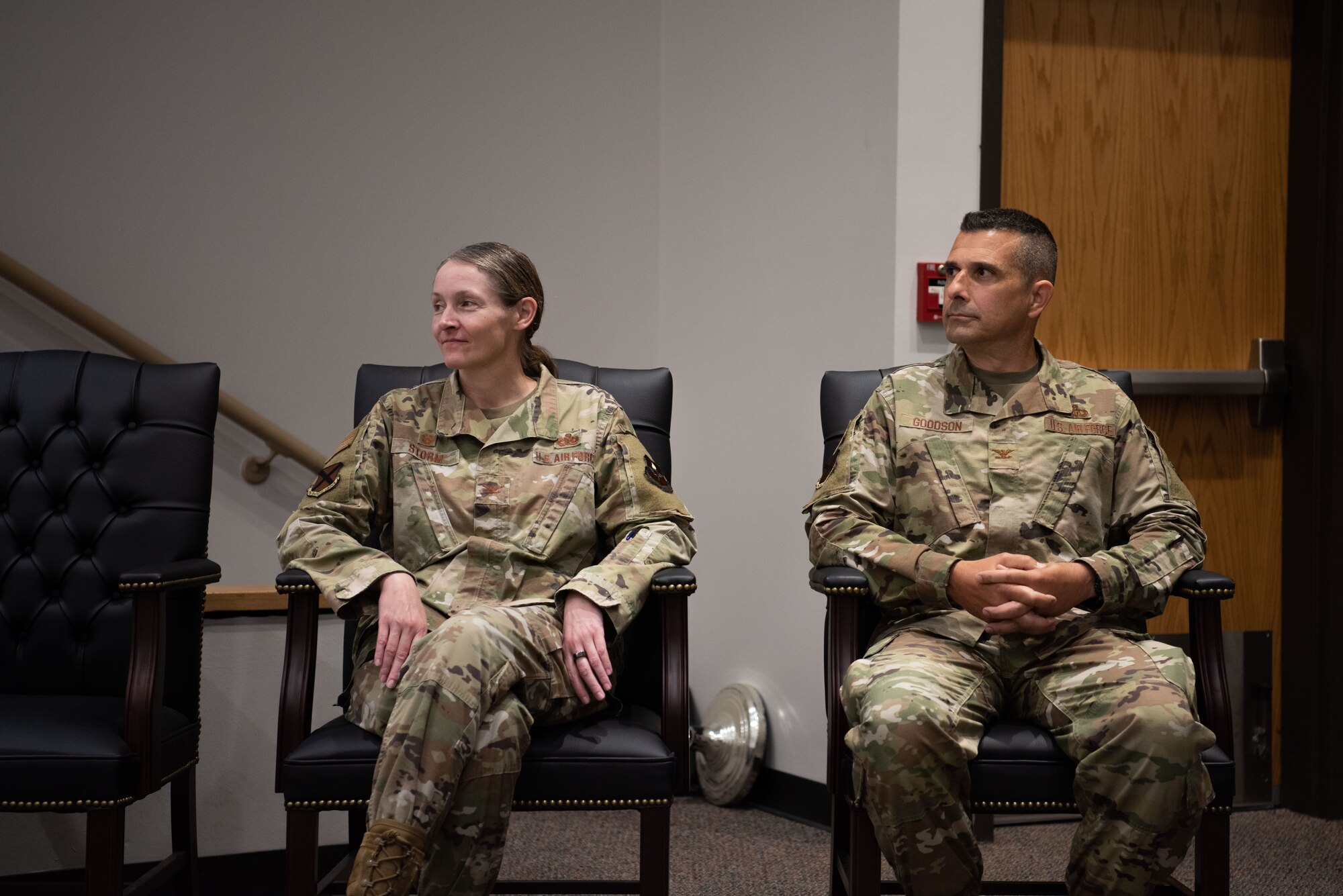 Two people sit in their chairs looking to their right at a speaker