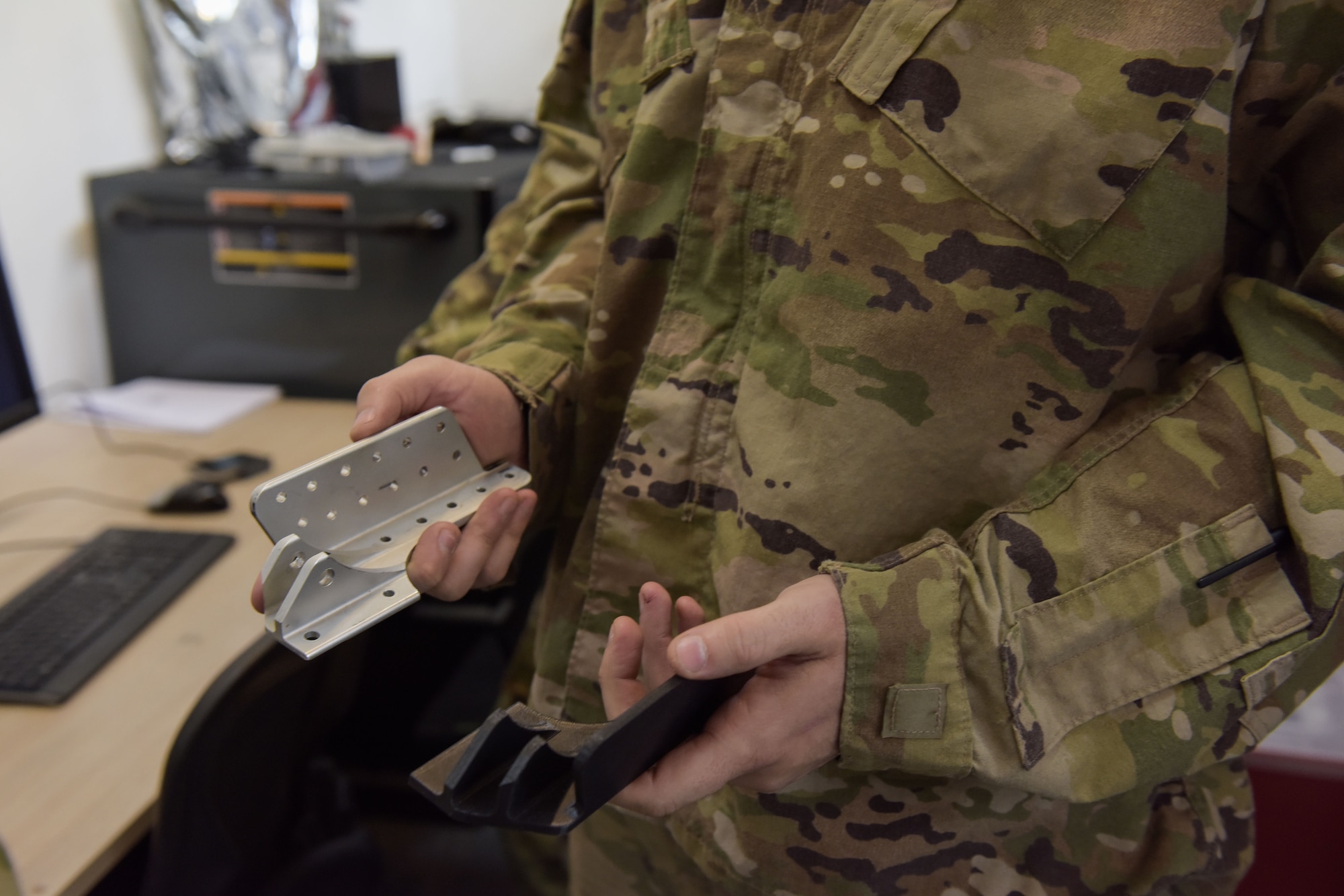 Man holds up two aircraft brackets