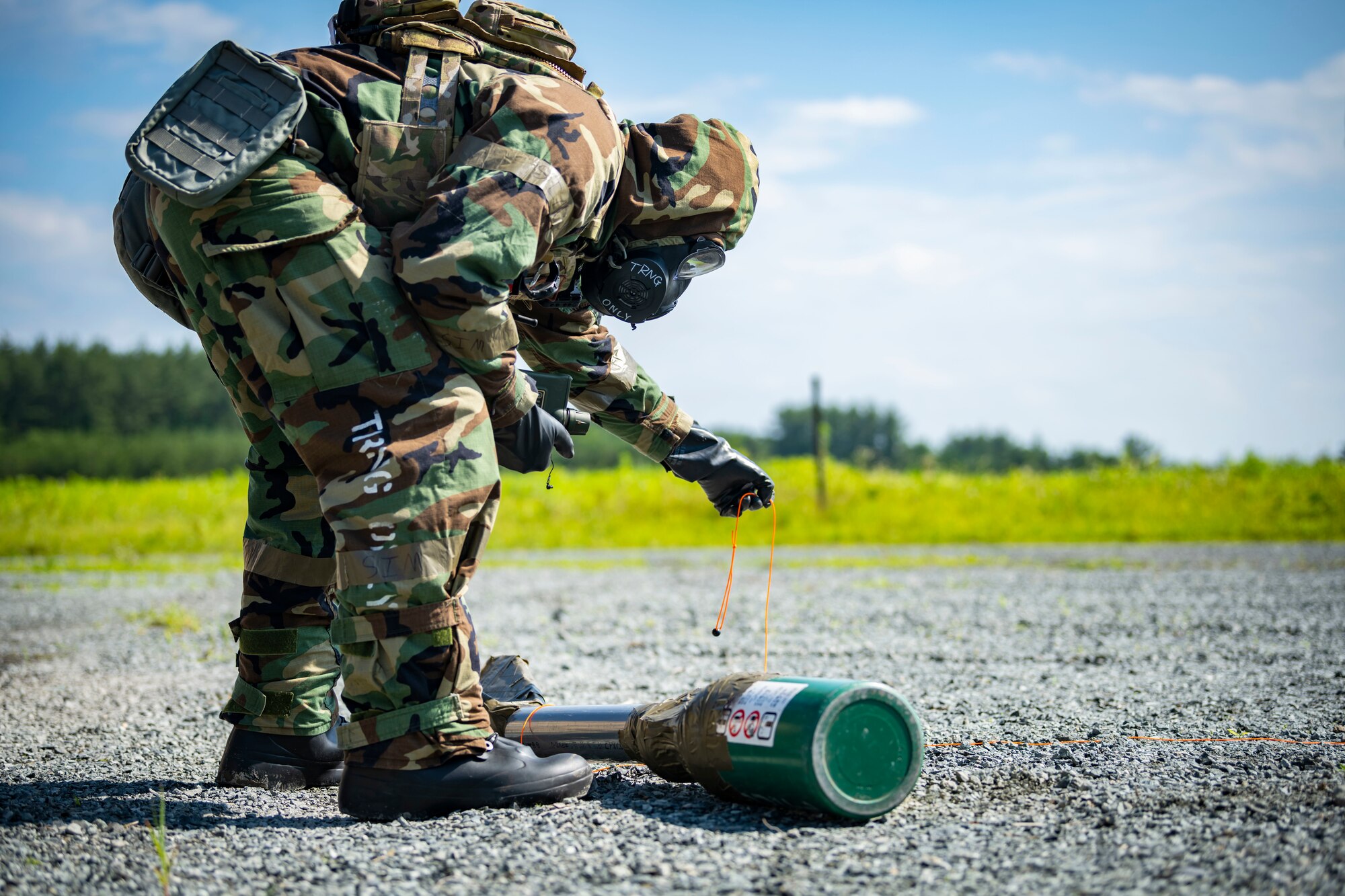 U.S. military member in chemical gear ties a chemical weapon with wire.