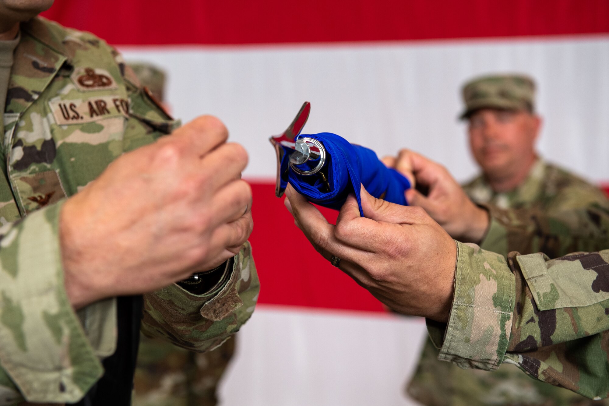 The 31st Aircraft Maintenance Squadron official guidon is furled up and stowed away to signify the squadron’s inactivation during the 31st Maintenance Group Reorganization Ceremony