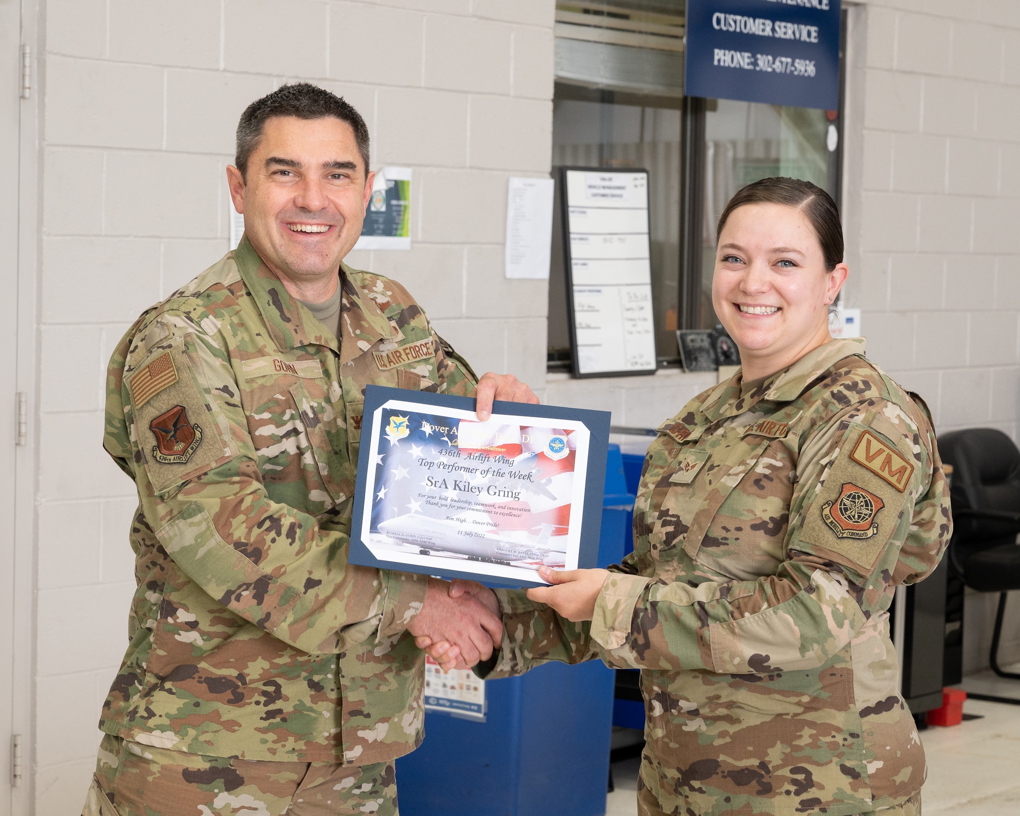 Col. Rusty Gohn, left, 436th Airlift Wing vice commander, presents Senior Airman Kiley Gring, 436th Logistics Readiness Squadron fleet management and analysis apprentice, with a certificate and coin as the week’s top performer at Dover Air Force Base, Delaware, July 27, 2022. Gring Was also was coined by Gohn for her outstanding performance. (U.S. Air Force photo by Mauricio Campino)