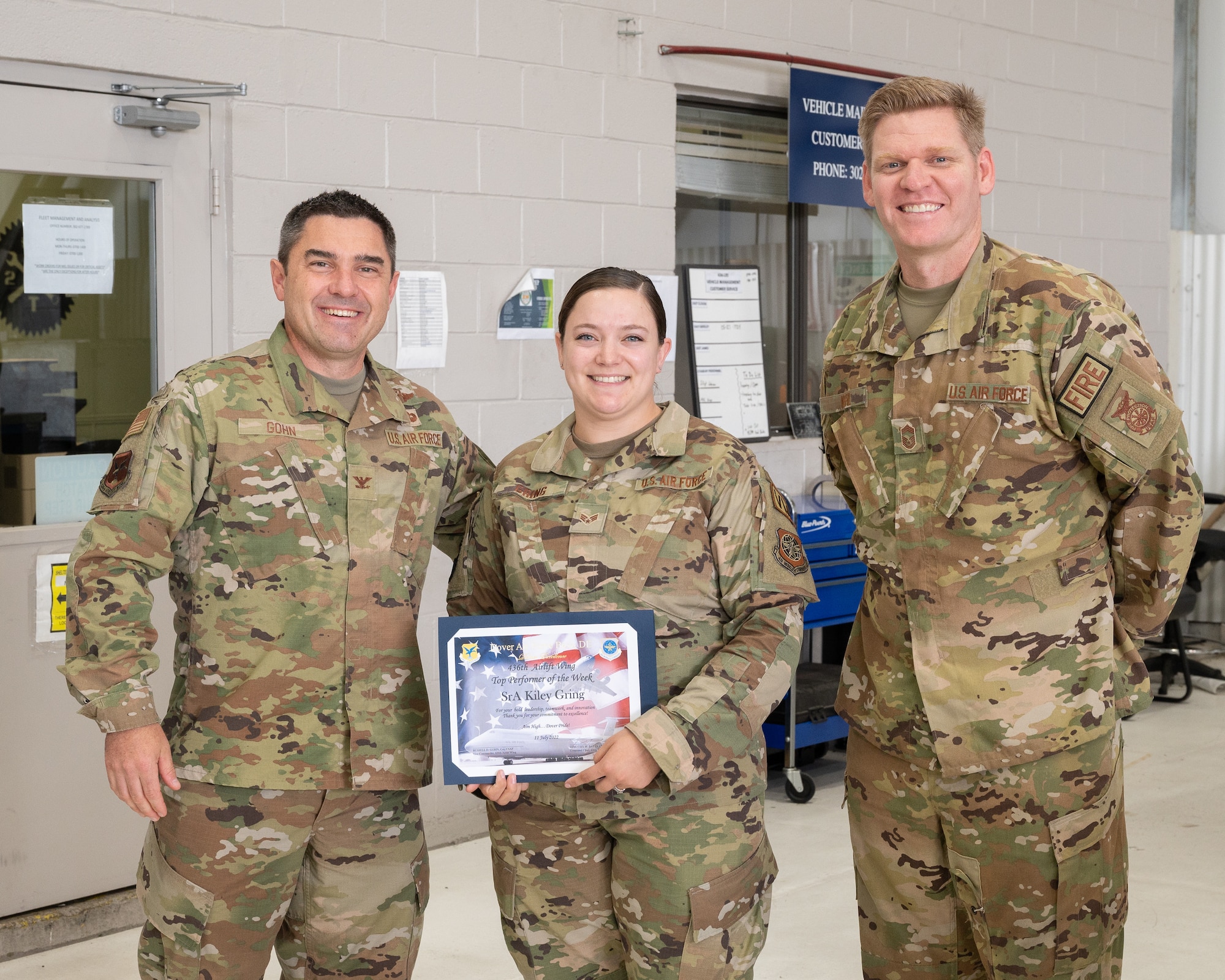 Col. Rusty Gohn, left, 436th Airlift Wing vice commander, and Chief Master Sgt. Andrew Kehl, right, 436th Civil Engineer Squadron fire chief, present Senior Airman Kiley Gring, 436th Logistics Readiness Squadron fleet management and analysis apprentice, with a certificate as the week’s top performer at Dover Air Force Base, Delaware, July. 27, 2022. Gohn presented Gring with a certificate and coin for being recognized as the week’s Top Performer. Accompanying Gohn was Chief Master Sgt. Andrew Kehl, right, 436th Civil Engineer Squadron fire chief.(U.S. Air Force photo by Mauricio Campino)
