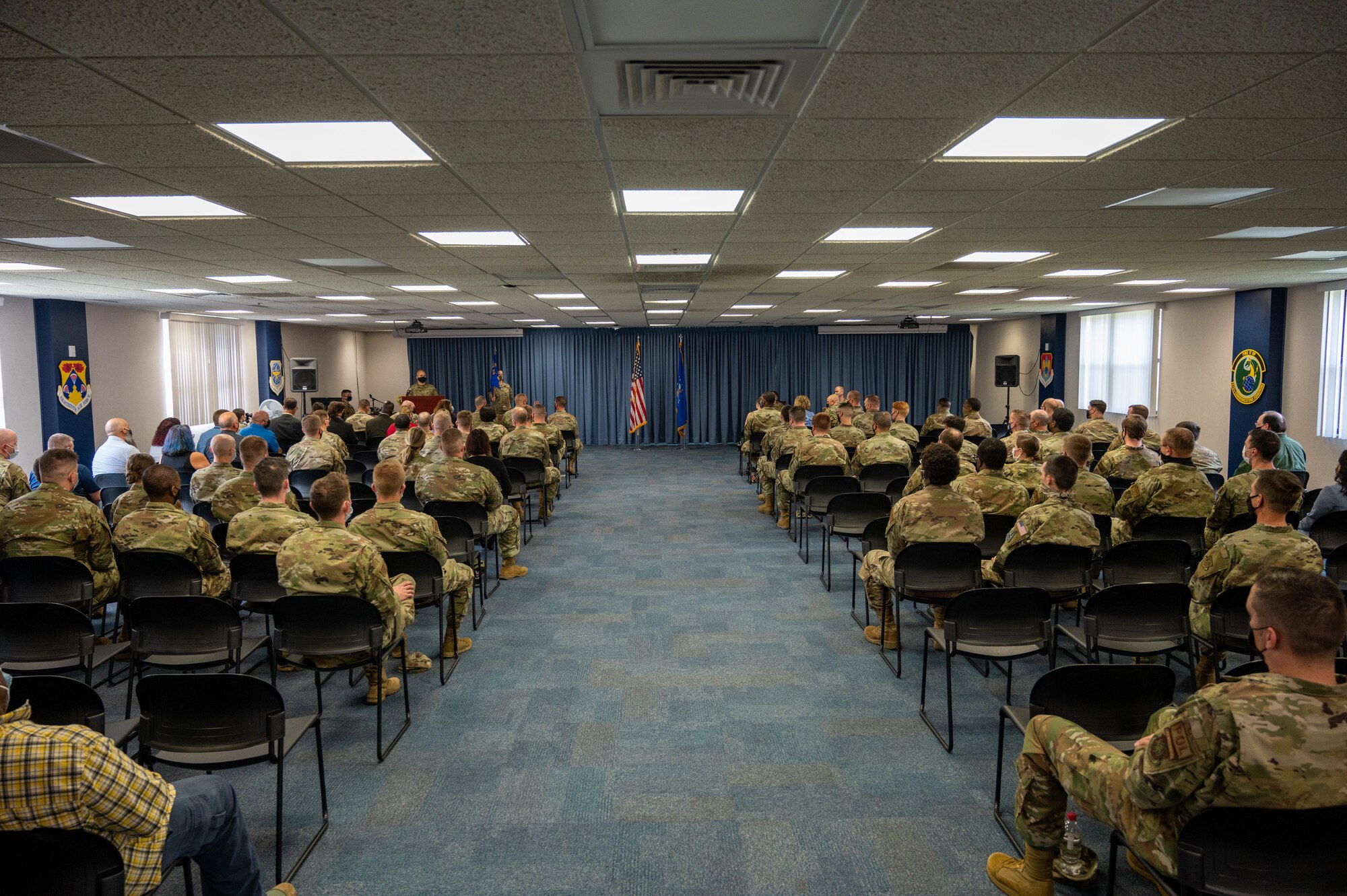 Group of people sit in room listening to M.C.