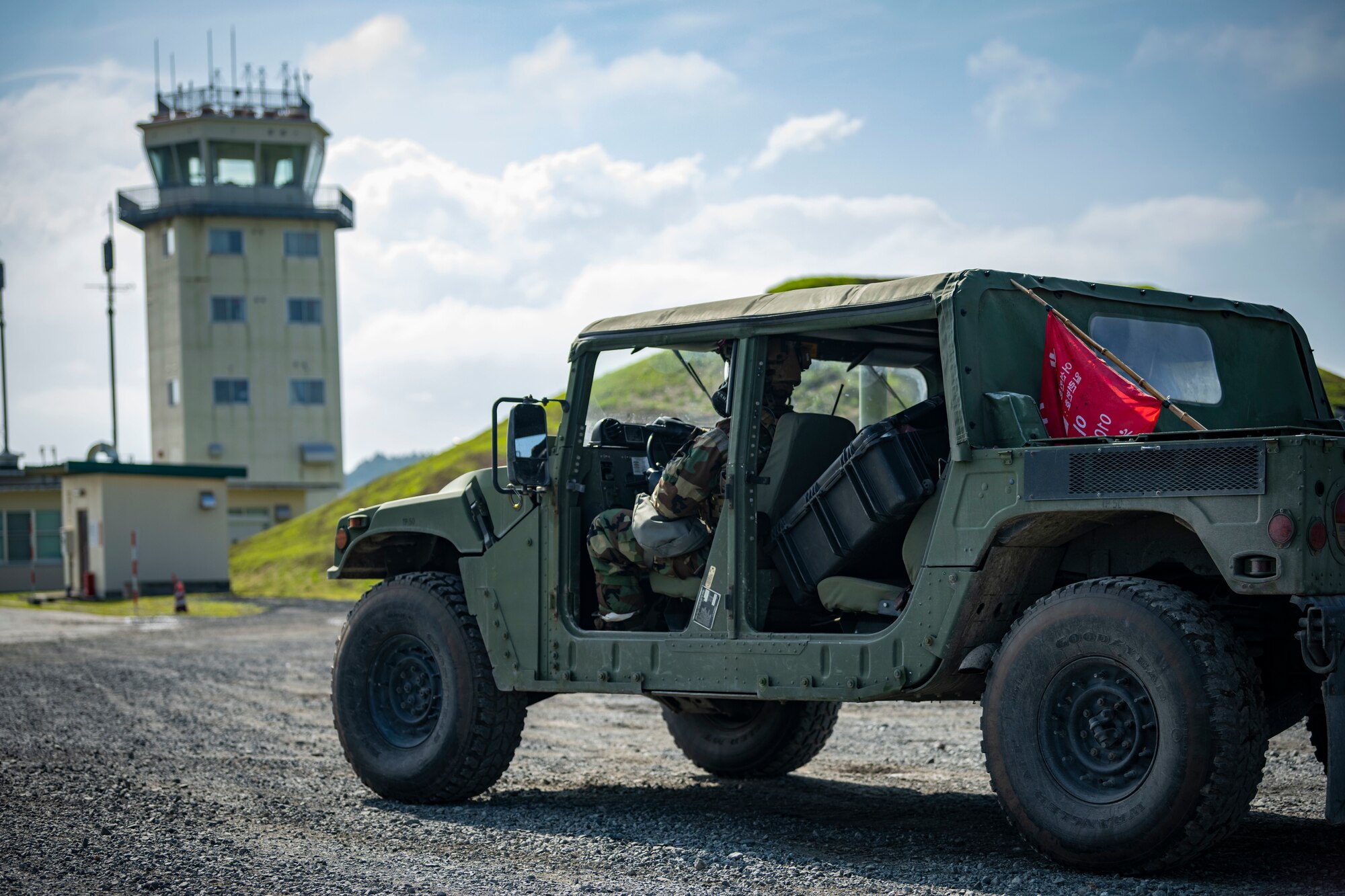 U.S. military members in chemical gear drive a Humvee away.
