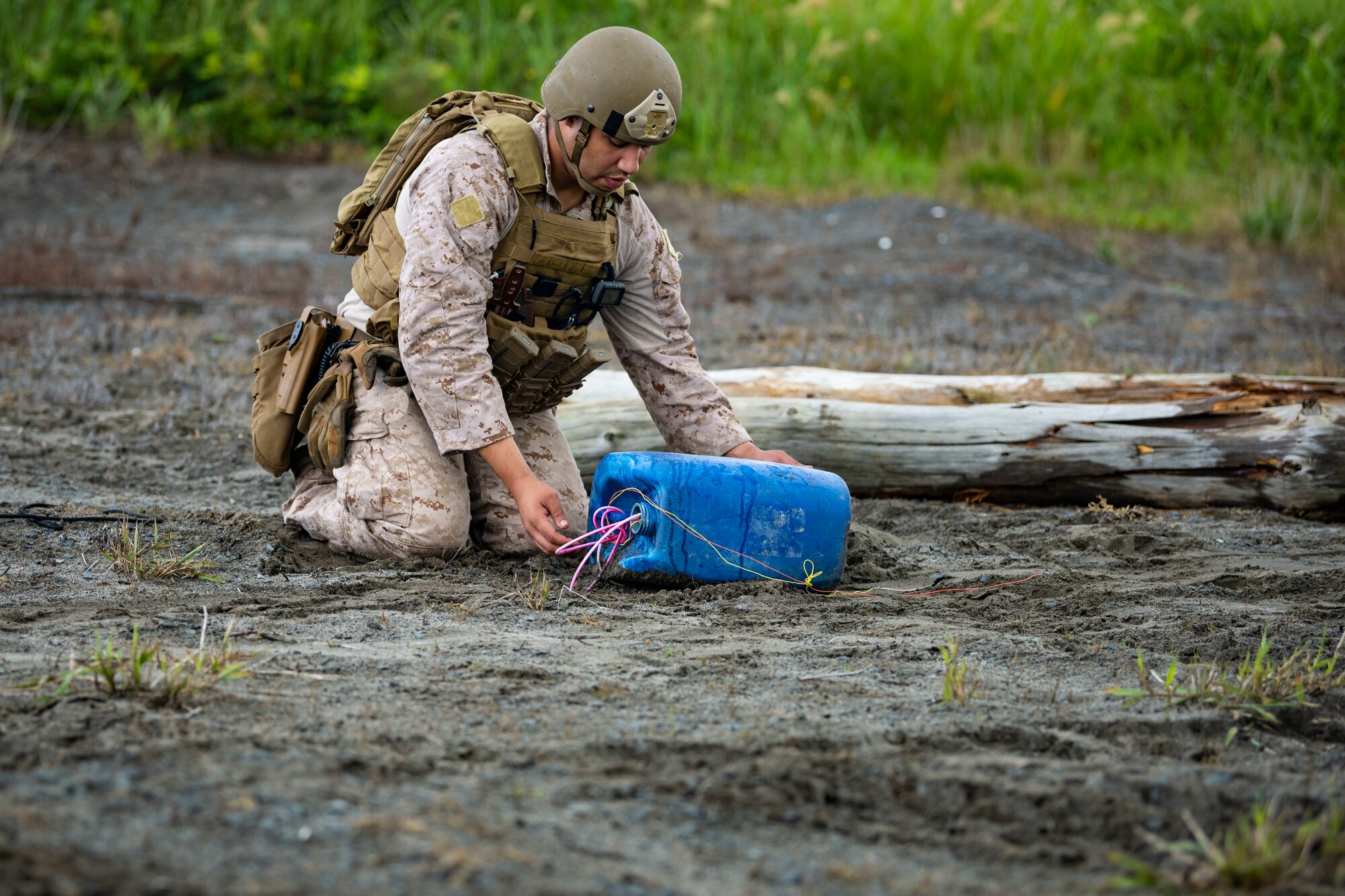 U.S. military member in tactical gear picks up an explosive ordnance.