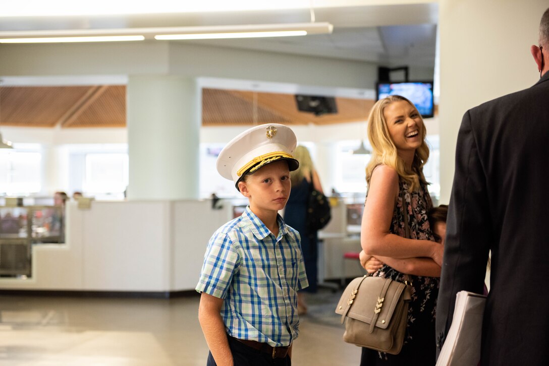 A boy wears a white Marine Corps hat and looks forlorn at the camera.