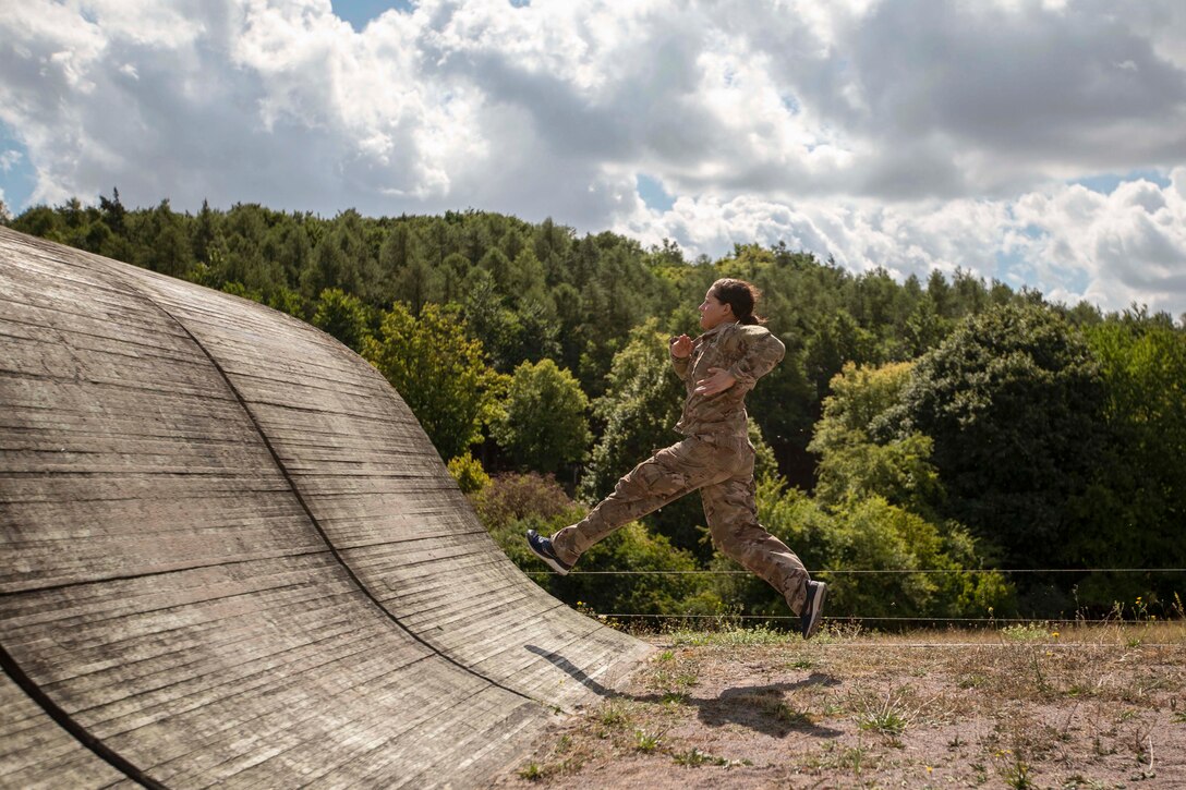 A soldier jumps on wall in a field during a competition.