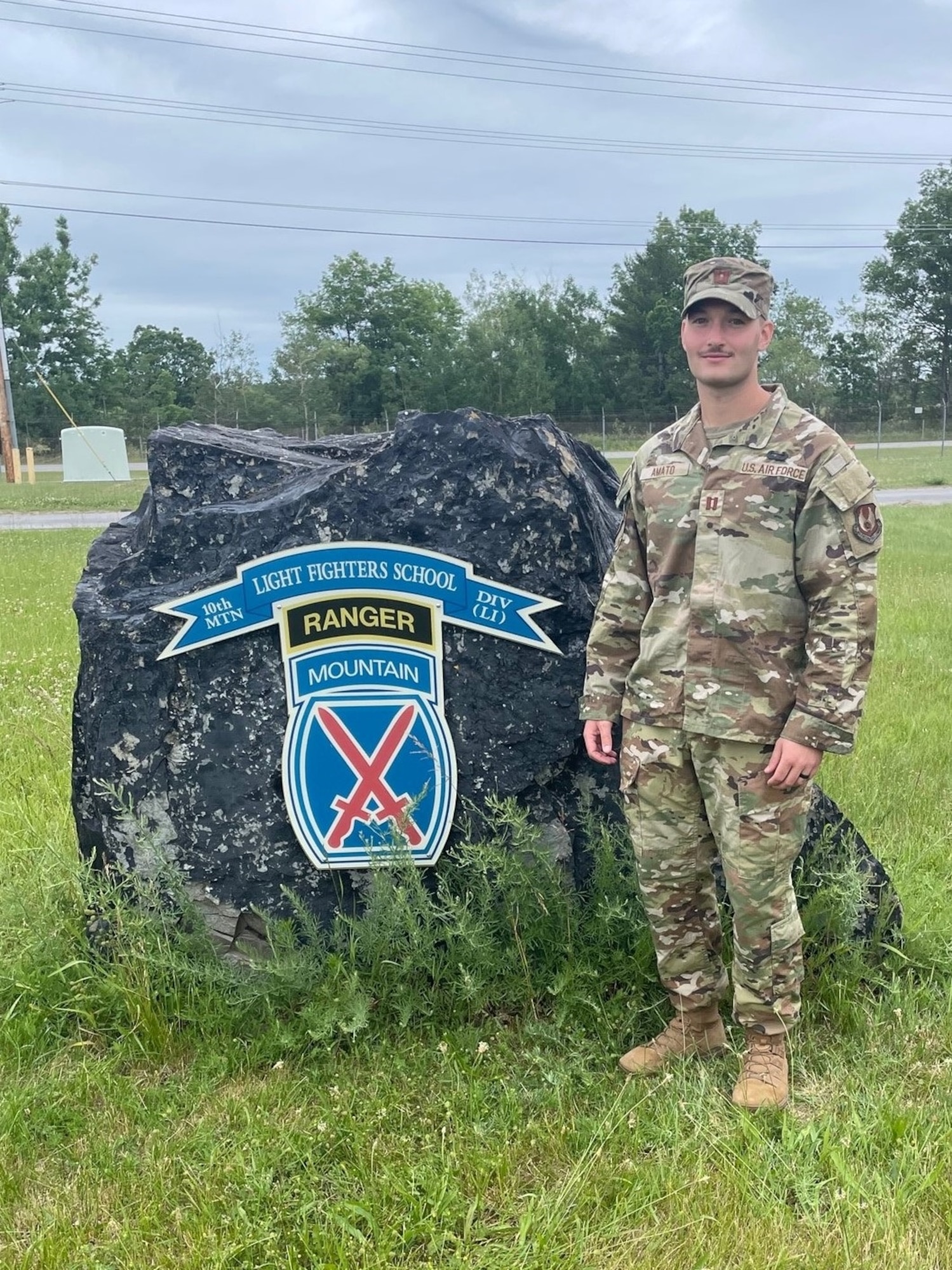 Capt. Evan Amato, Battlefield Airborne Communications Node cost analyst at Hanscom Air Force Base, Mass., stands in front of the Light Fighters School sign at Fort Drum, New York. In June, Amato earned his Air Assault wings after completing U.S. Army Air Assault School. (Courtesy photo)
