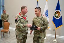 Col. Douglas Copeland, outgoing Project Manager for Soldier Maneuver and Precision Targeting (PM SMPT), turns over the organizational charter to Brig. Gen. Christopher Schneider, Program Executive Officer (PEO) Soldier, during a relinquishment of charter ceremony held on Fort Belvoir, July 14. The ceremony marked the disestablishment of PM SMPT after more than 20 years of providing Soldiers with capabilities designed to enhance lethality, mobility and survivability. (U.S. Army Photo by Jason Amadi, PEO Soldier Public Affairs)