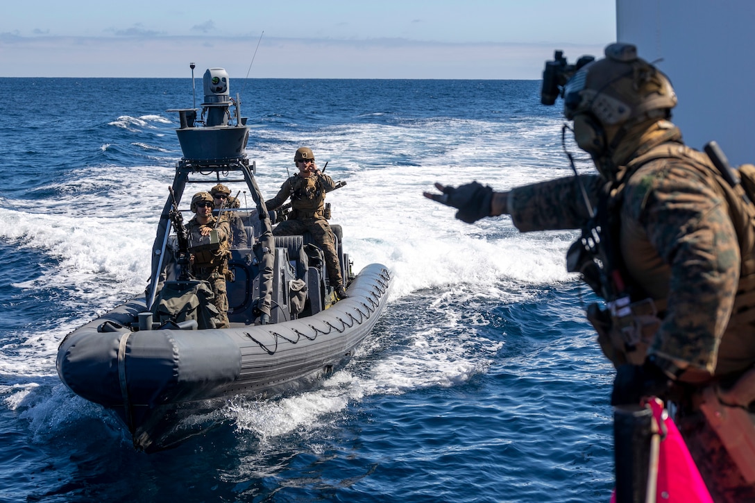 A U.S. Marine with All Domain Reconnaissance Company, 13th Marine Expeditionary Unit, uses hand signals to communicate with his team in a Rigged Hulled Inflatable Boat during a Maritime Interception Operation exercise July 12. The 13th MEU is currently embarked aboard the Anchorage, conducting routine operations in U.S. 3rd Fleet.
