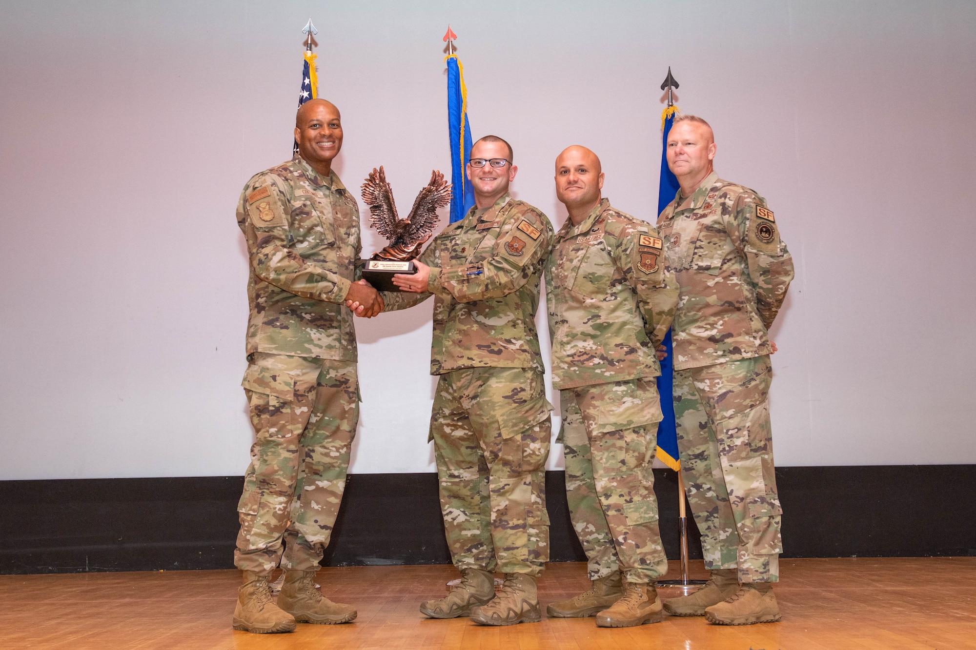 Brig. Gen. Roy W. Collins, Director of Security Forces, deputy chief of staff for logistics, engineering and force protection, headquarters U.S. Air Force and Chief Master Sgt. Donald Gallagher, 20th Security Forces career field manager present the 2021 Air Force Best Medium Security Forces Unit award to Maj. Rudy McIntyre, 28th Security Forces Squadron commander at Ellsworth Air Force Base, S.D., July 27, 2022.