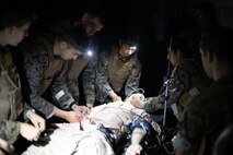 U.S. Navy Sailors with Bravo Surgical Company, 3d Medical Battalion, 3d Marine Logistics Group, assess and treat a simulated casualty during a nighttime medical treatment training event, Marine Corps Base Hawaii, July 19, 2022. The training was conducted in order to familiarize members of Bravo Surgical Company with patrolling, resuscitation, surgical treatment, and evacuation of injured service members in a nighttime environment. (U.S. Marine Corps photo by Cpl. Brandon Aultman)