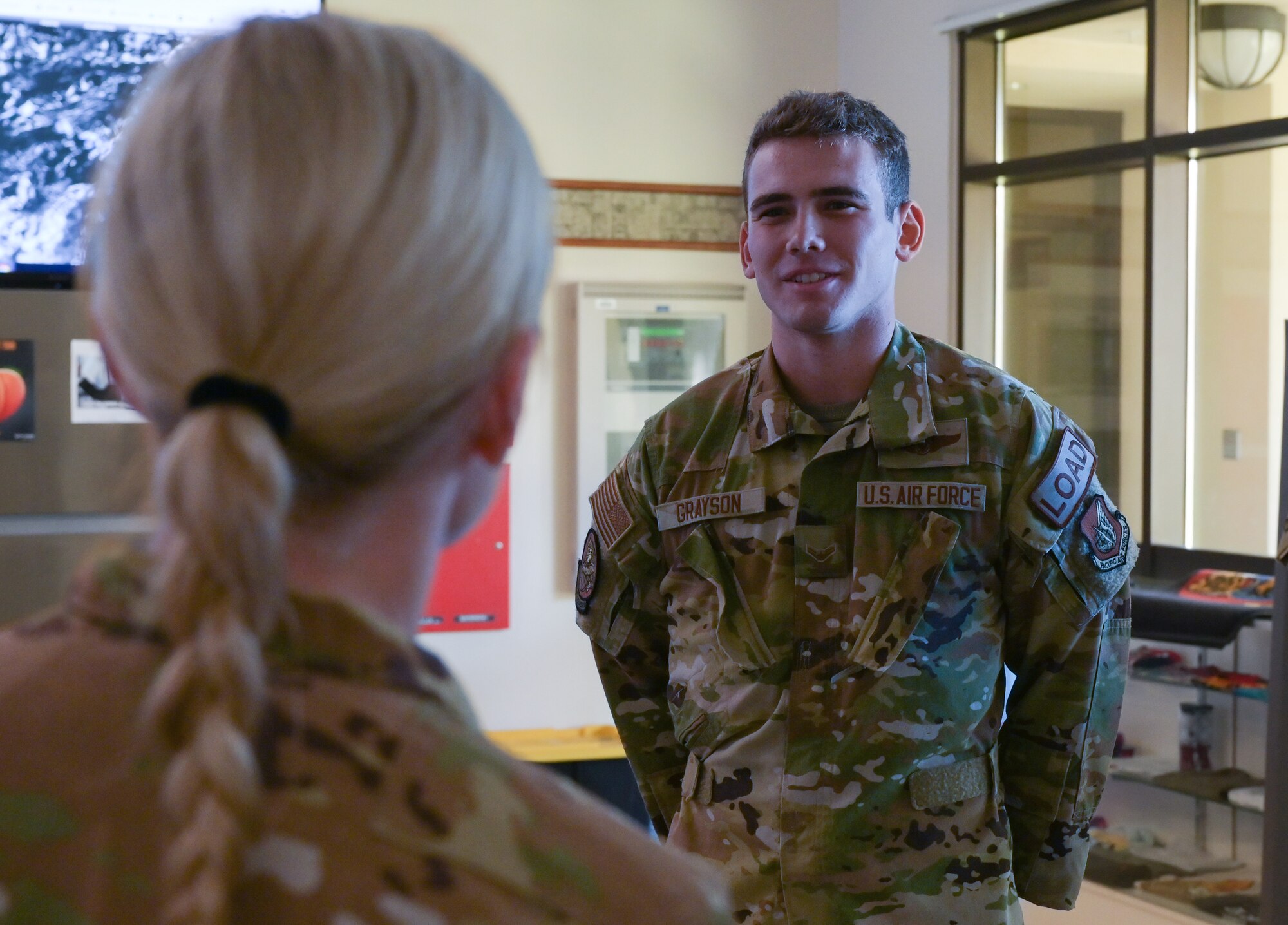 Airman 1st Class Jace Grayson, 535th Airlift Squadron loadmaster, receives a coin from Col. Michele Lo Bianco, 15th Wing commander, at Joint Base Pearl Harbor-Hickam, Hawaii, July 19, 2022. Grayson, a sailor and four more JBPHH Airmen assisted Diane Heard, 15th Wing Violence Prevention investigator, after she injured her ankle and knee during a hike. (U.S. Air Force photo by Staff Sgt. Alan Ricker)