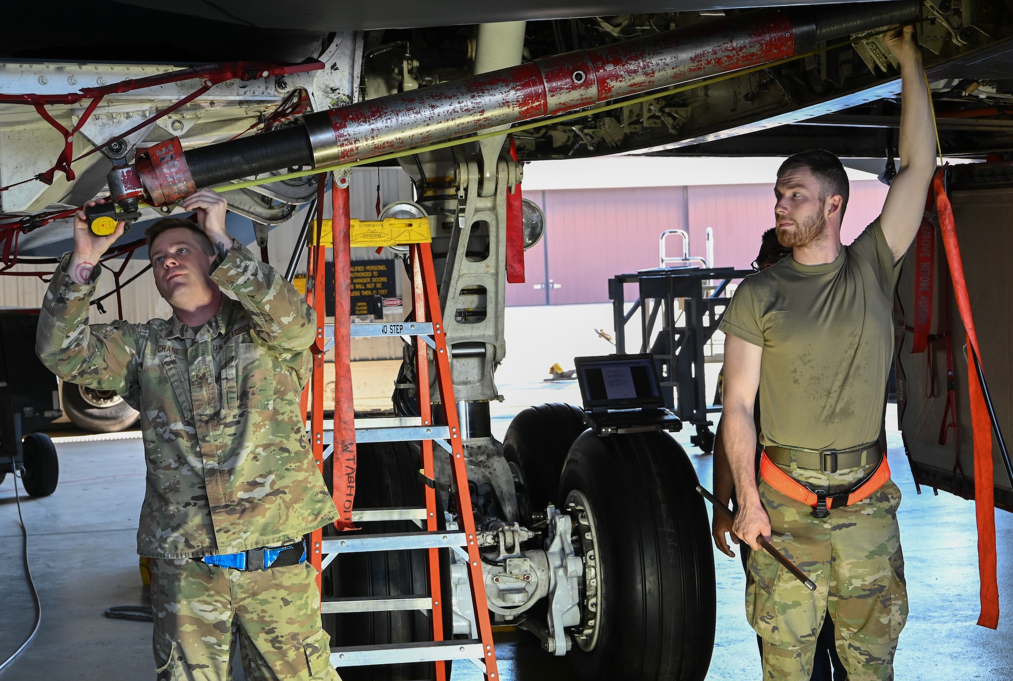 Staff Sgt. Robert Crane and A1C Elijah Austin measure a component on the B-2 Spirit at Whiteman Air Force Base, Missouri, July 20, 2022. The 509th Maintenance Group uses attention to detail to make sure B-2's are always in flying condition. (U.S. Air Force photo by Airman 1st Class Joseph Garcia)