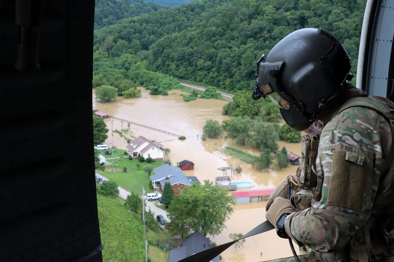 A Kentucky National Guardsman looks out from an in-flight helicopter at flooding below.