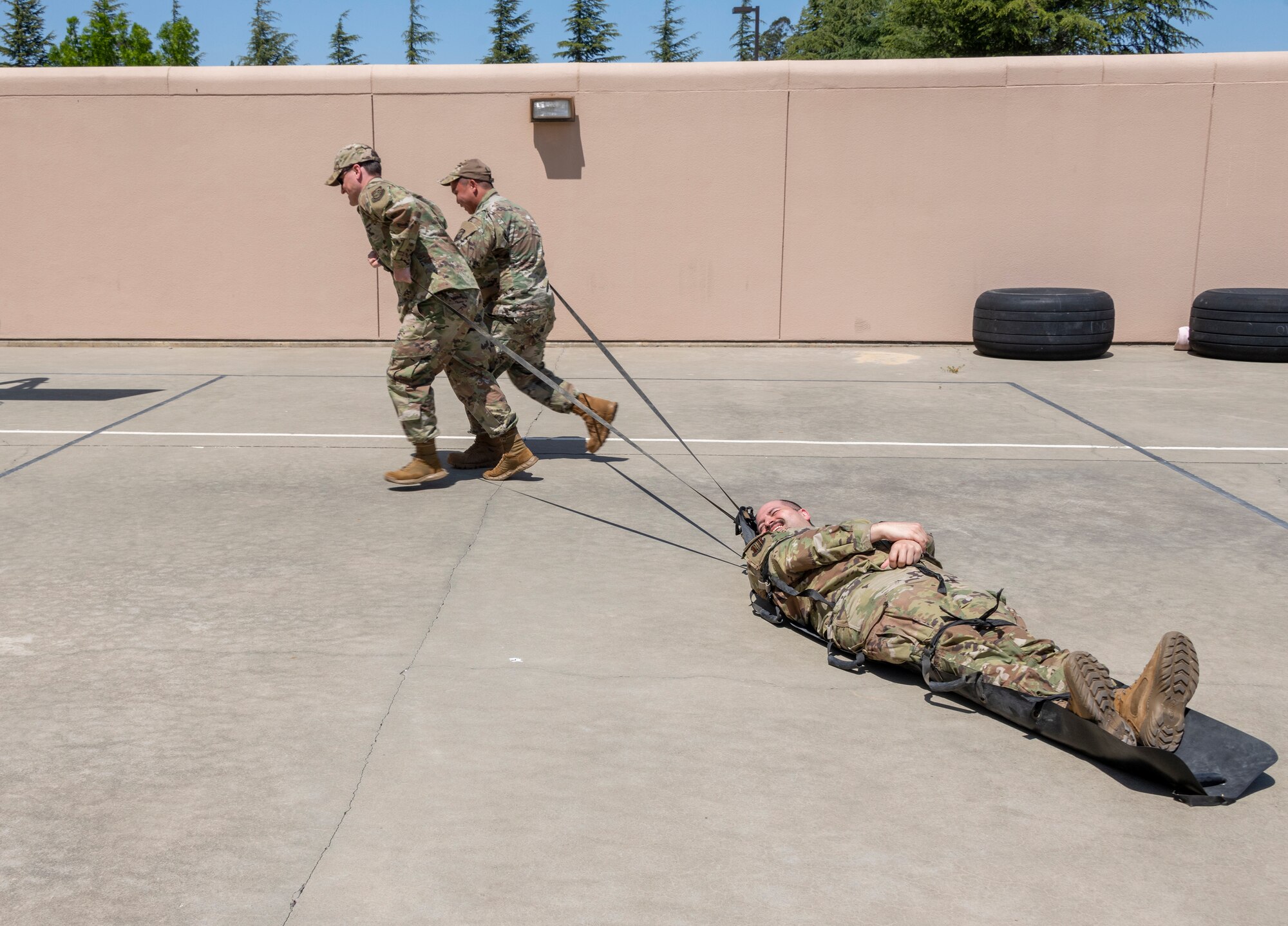 Airmen pull an Airman on a portable human transporting system.