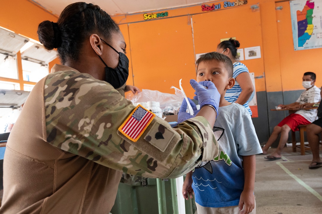 A soldier gives medicine to a young boy.