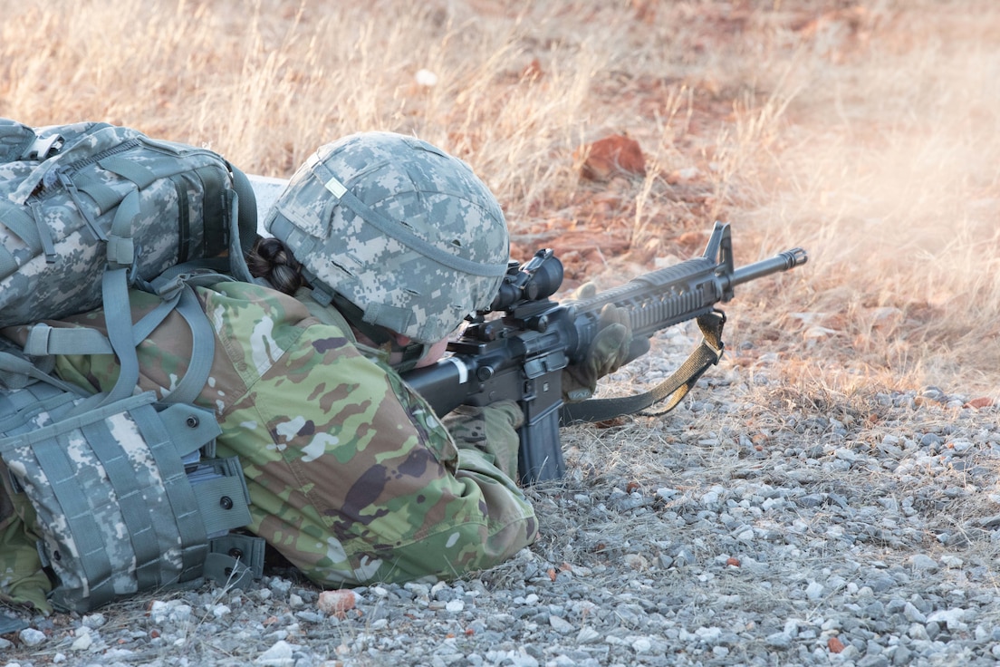 Soldier lays on the ground firing a rifle