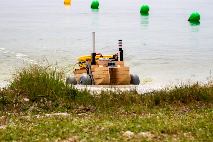 Naval Surface Warfare Center Panama City Division A Department's – “The Bandits” – amphibious vehicle transitions from water to land at Naval Support Activity Panama City, Fla., during preliminary trials of the Technical Director's Cup, May 17, 2022. The basic concept of our robot is a duck boat. The challenge involved transitioning from sea to land and we approached this with an amphibious design. In essence, it’s a pontoon boat with wheels, stated A Department Team Captain Jared Wampler. (U.S. Navy photo by Bob Lindee)