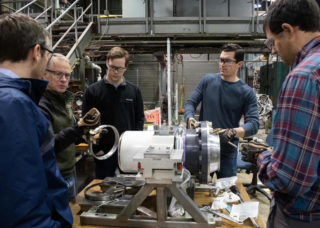 A senior engineer with Core Parts, explains what he is working on while assembling an instrumented small engine test stand, March 9, 2022, in the Propulsion Research Facility.