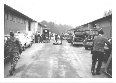 People waiting outside by their cars.