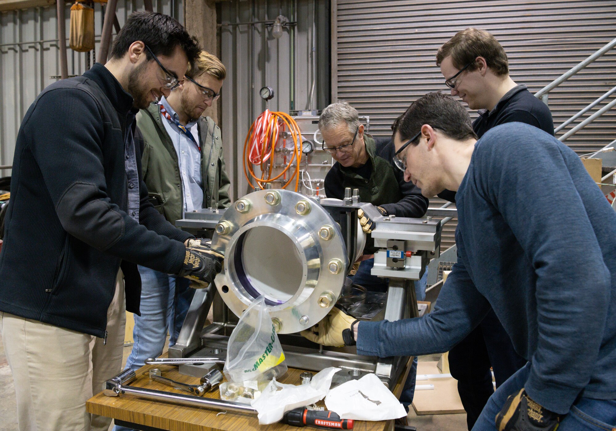 AEDC team members and an engineer with small business Core Parts bolt a flange into place while assembling an instrumented small engine test stand, March 9, 2022, in the Propulsion Research Facility at the University of Tennessee Space Institute.