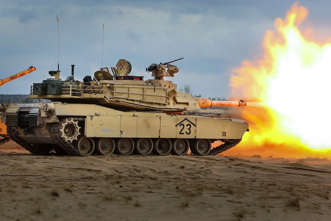 A tank fires its weapon in a desert.