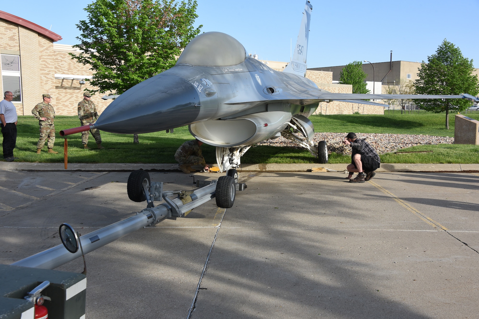 A U.S. Air Force F-16 is removed from static display and moved to paint facility.