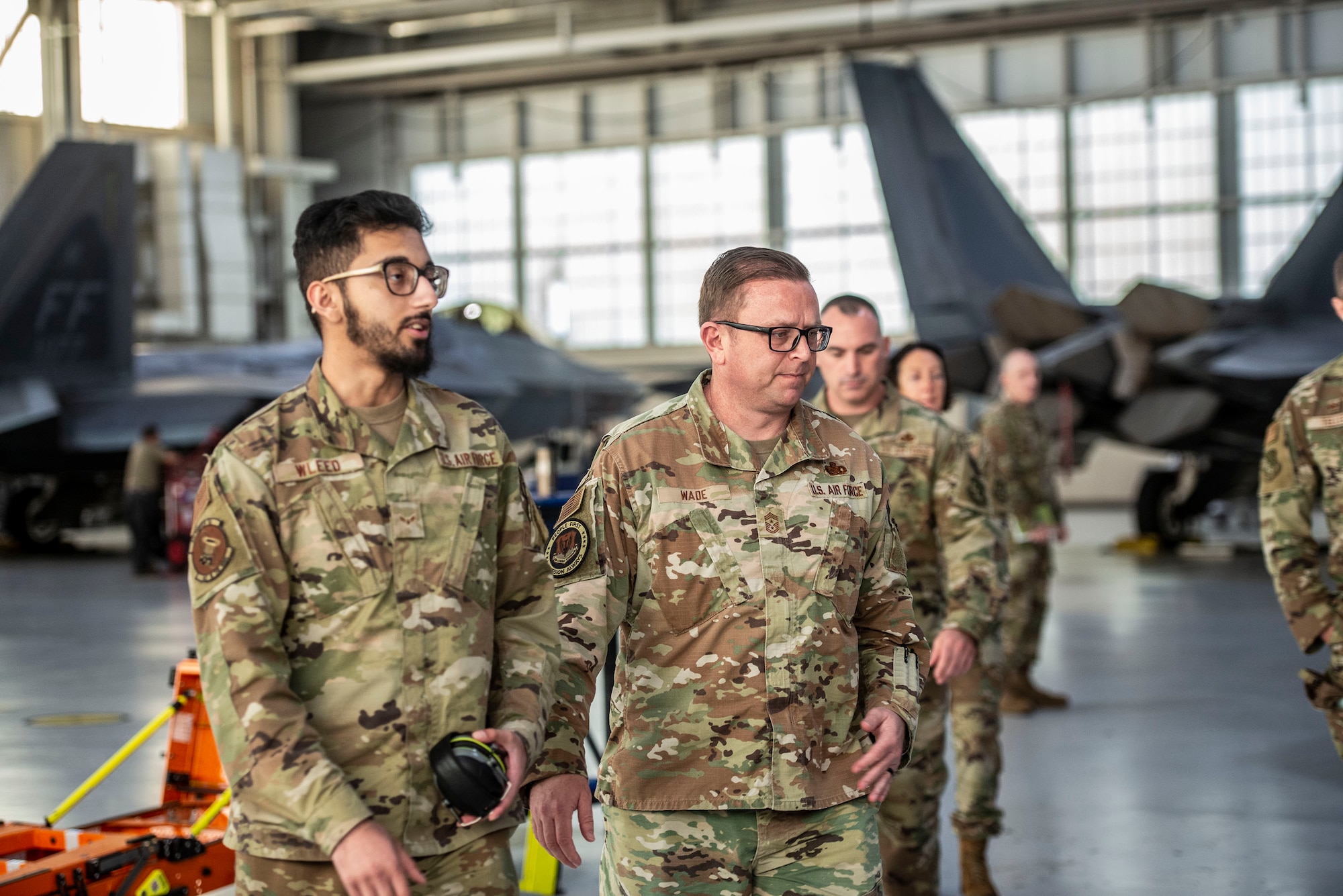 Airmen walk inside a hangar.