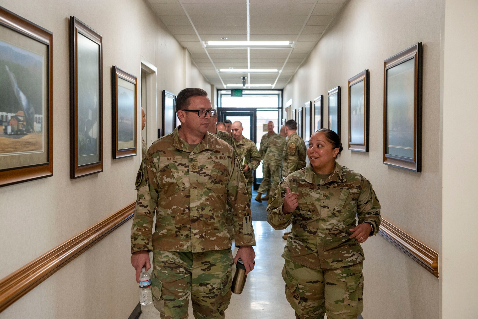Two Airmen walk down the hall.