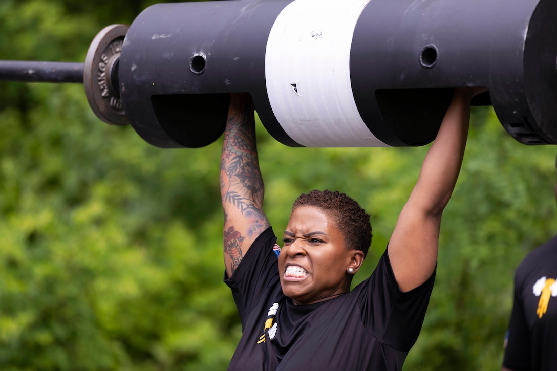 A soldier lifts a log press during a competition.