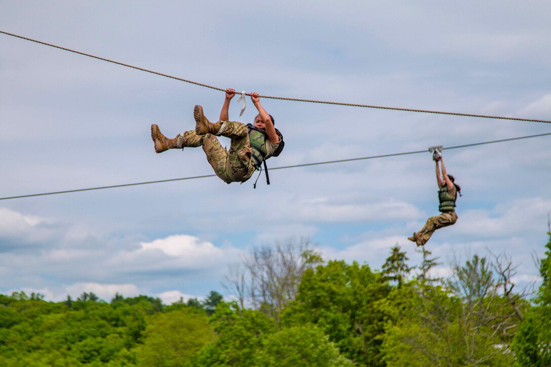 Two Army cadets move down a zipline.
