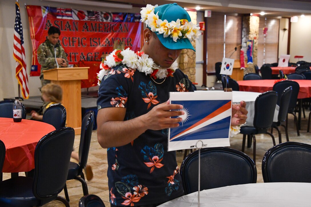 U.S. Air Force Airman 1st Class Ramel Alfred, 97th Comptroller Squadron financial management technician, places a Marshall Islands flag on a stand during the “Taste of Asia” event as part of Asian American and Pacific Islander (AAPI) Heritage Month at Altus Air Force Base, Oklahoma, May 31, 2022. The event featured many types of foods including spam musubi, Hawaiian chicken, egg rolls and more. (U.S. Air Force photos by Airman 1st Class Miyah Gray)