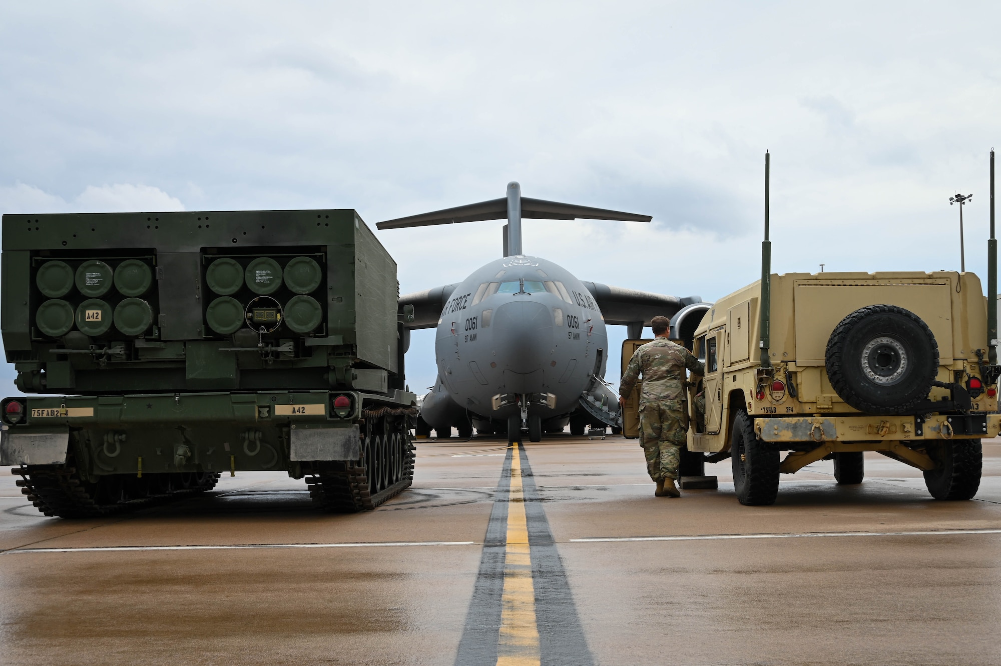 An M142 High Mobility Artillery Rocket System (HIMARS) and humvee park outside a C-17 Globemaster III at Altus Air Force Base, Oklahoma, May 25, 2022. The HIMARS carries six rockets or one large missile in a five-ton truck, and can launch the entire Multiple Launch Rocket System Family of Munitions which includes more than 10 different types of rockets. (U.S. Air Force photo by Senior Airman Kayla Christenson)