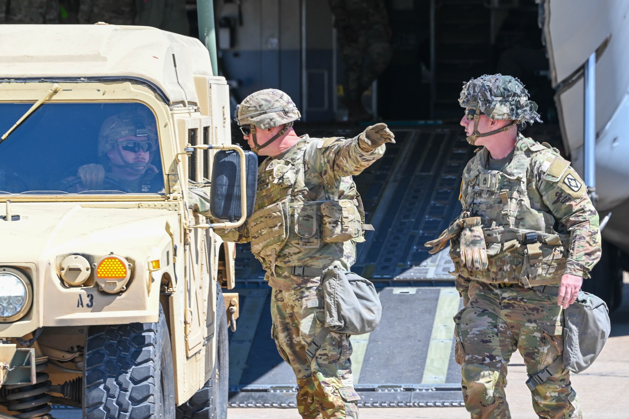 Soldiers talk outside a C-17 Globemaster III at Fort Sill, Oklahoma, May 26, 2022. Two C-17s flew to Fort Sill to deliver two M142 High Mobility Artillery Rocket Systems and two humvees. (U.S. Air Force photo by Senior Airman Kayla Christenson)