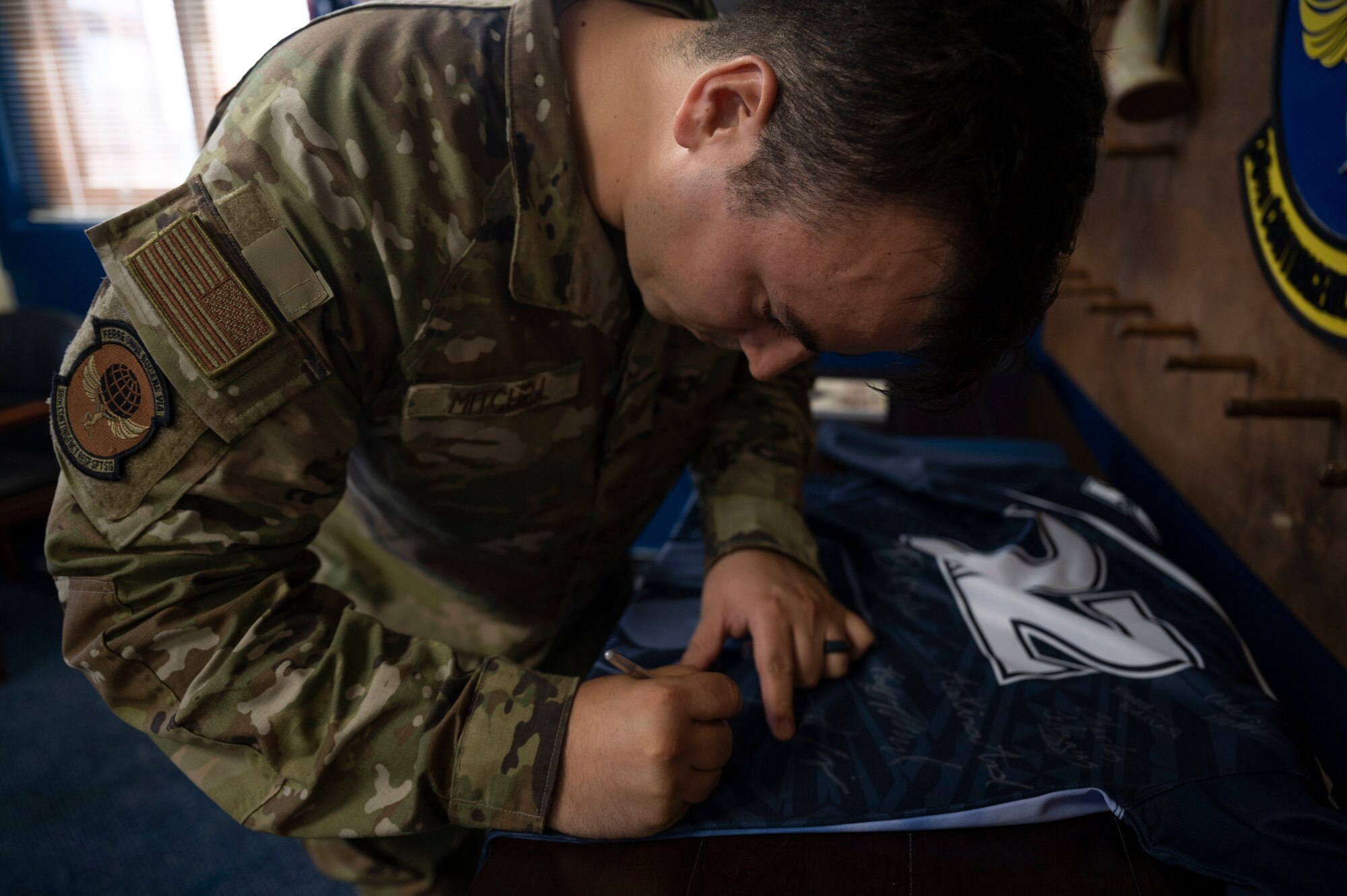 U.S. Air Force Tech. Sgt. Lucas Mitchell, the noncommissioned officer in charge of intel mission operations with the 36th Contingency Response Support Squadron, signs the Linebacker of the Week jersey after receiving the award at Andersen Air Force Base, Guam, May 25, 2022.