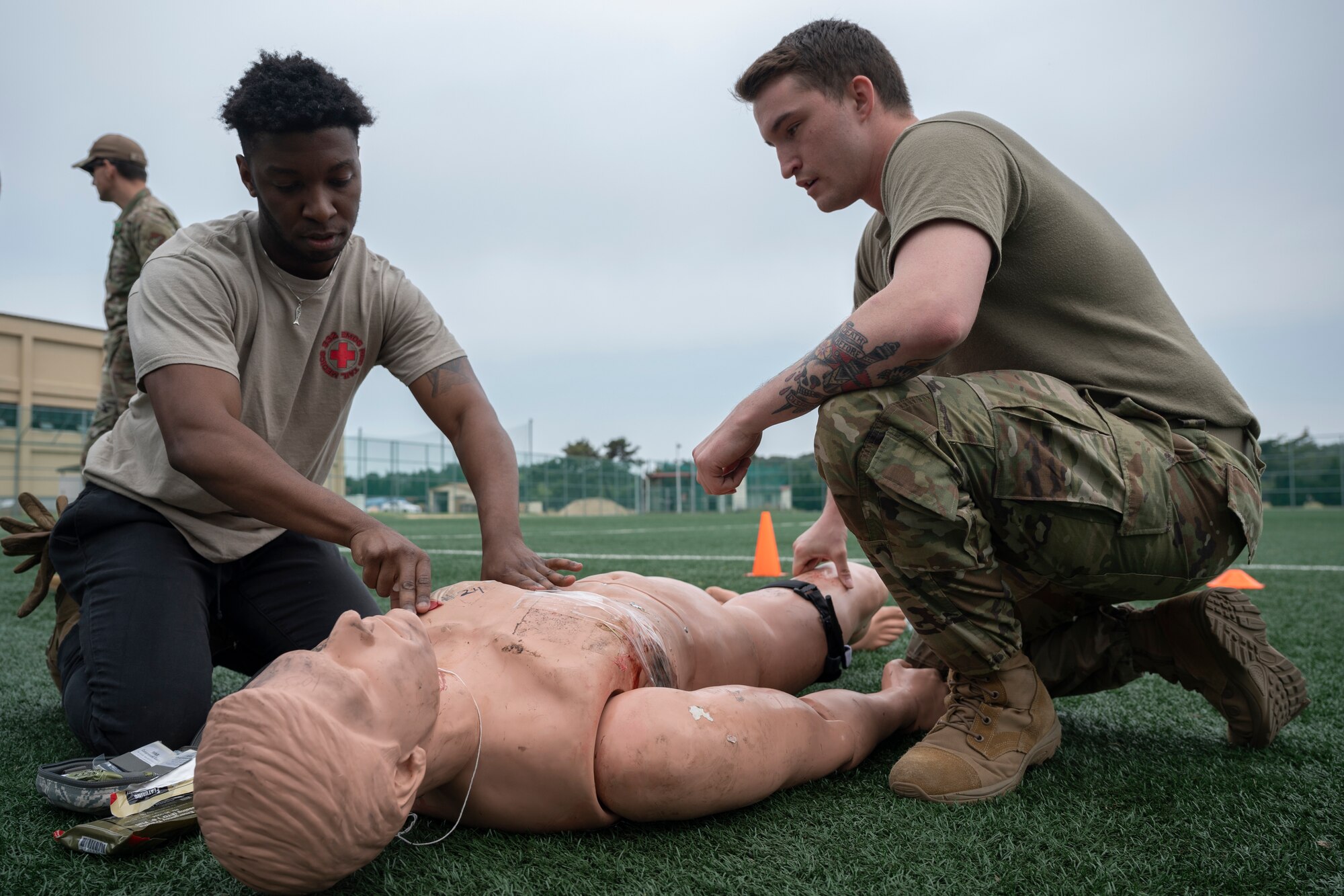 Two Airmen practice Tactical Combat Casualty Care medical training on a practice dummy.