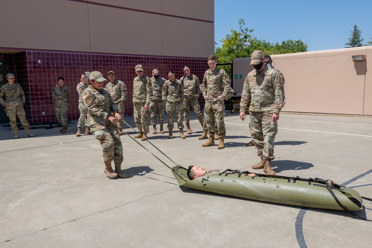 U.S. Air Force Airman Josefina Toboada-Torres, left center, 60th Dental Squadron dental assistant, uses a basic stretcher rescue system to drag Senior Airman Min Son, 60th Medical Support Squadron medical logistician, during tactical combat casualty care training at David Grant USAF Medical Center, Travis Air Force Base, California, April 28, 2022.