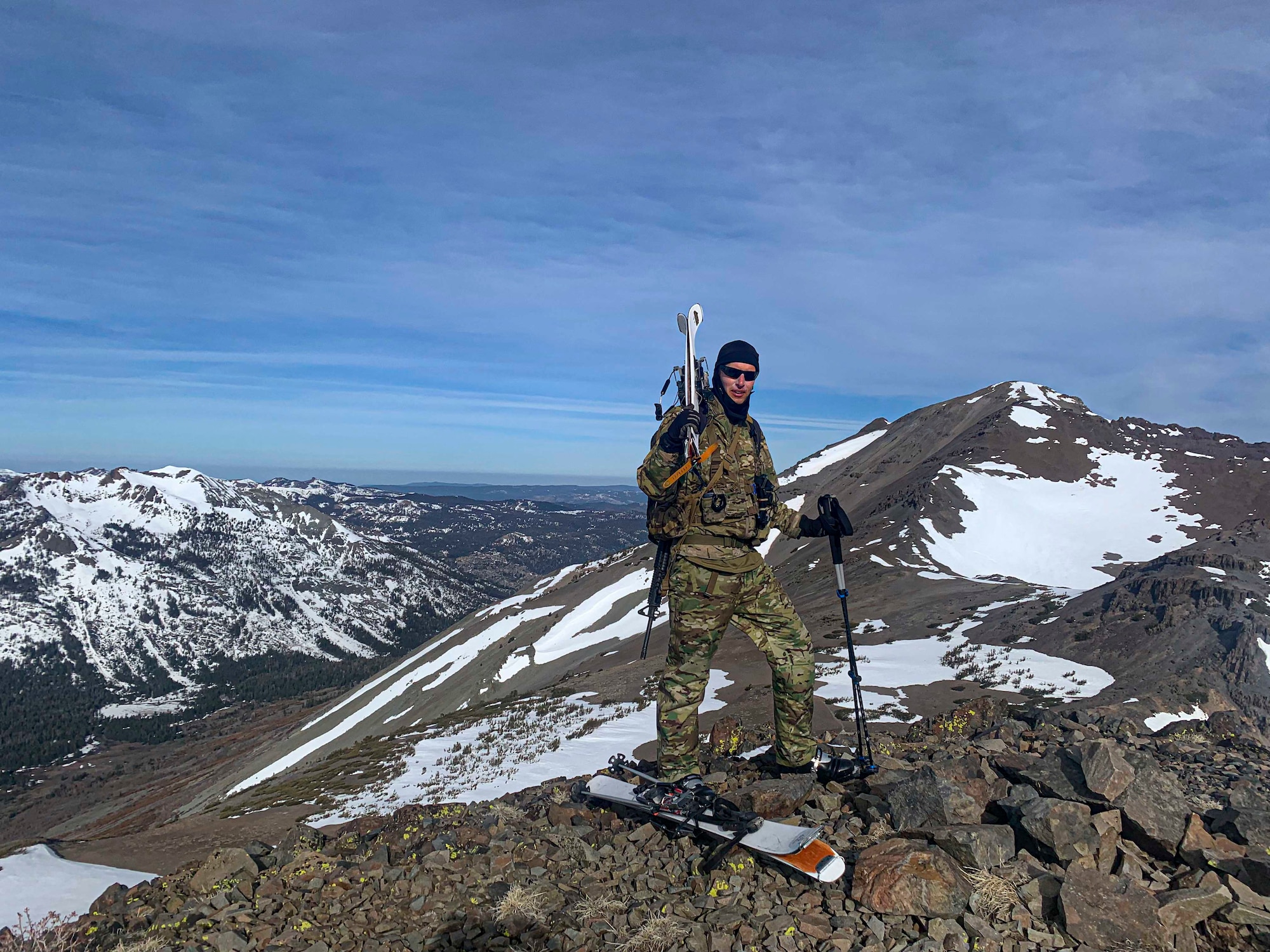 A photo of an Airman posing for a photo on top of a snowy mountain.