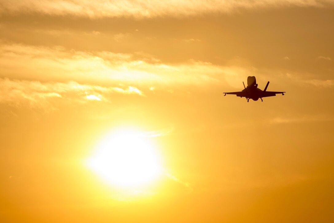 An aircraft flies under a sunlit sky.